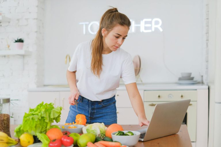 Nutrition coach working on a nutrition plan with a laptop and fresh ingredients