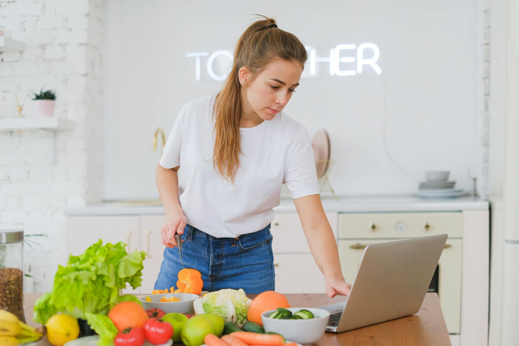 Voedingscoach werkt met laptop en verse ingrediënten aan een voedingsplan